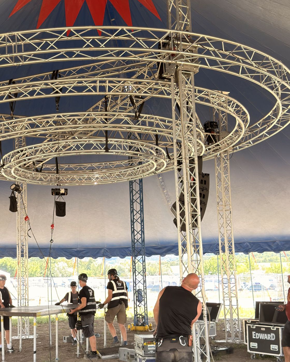 Technicians assembling circular truss on the floor in a tent