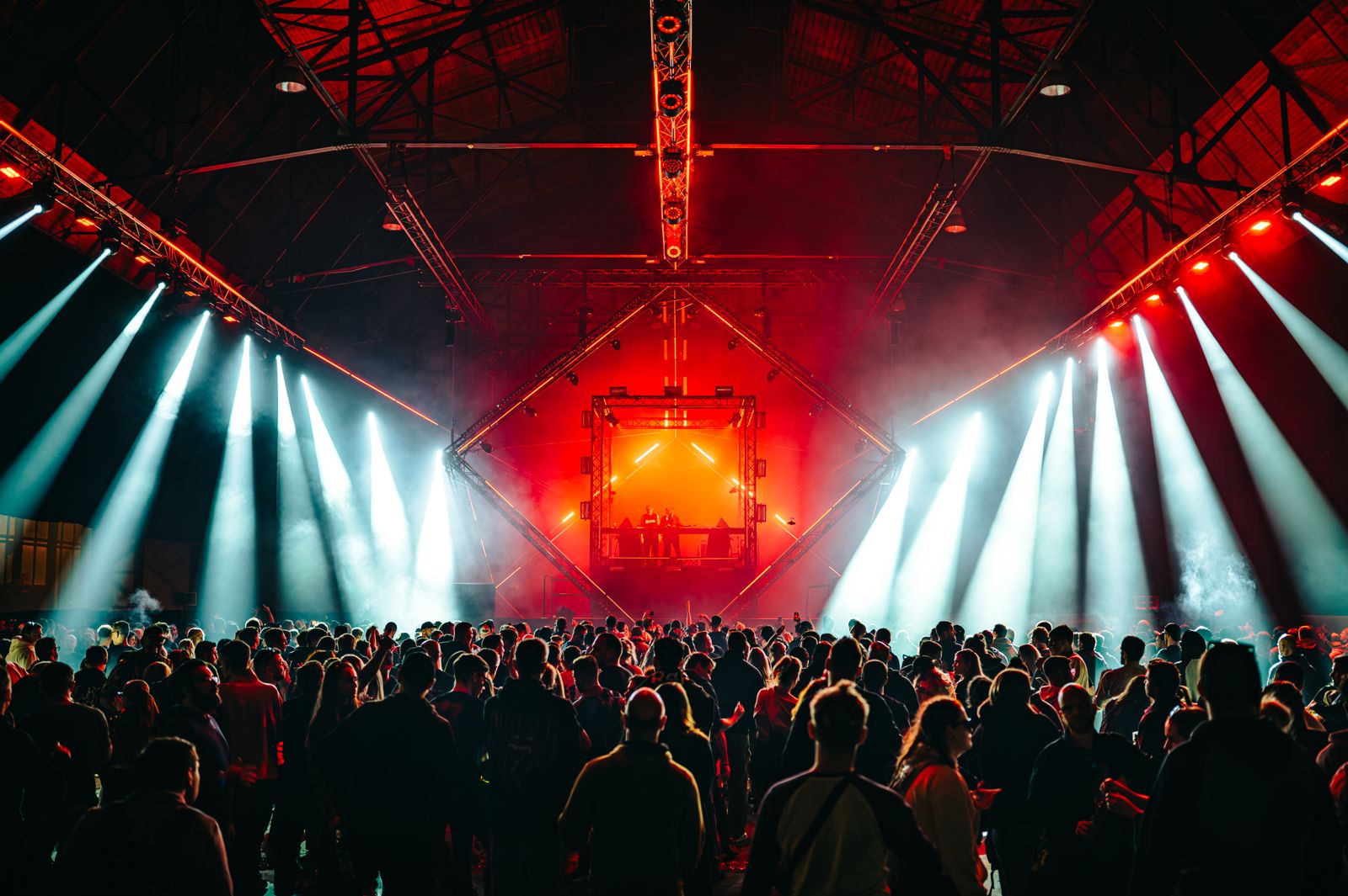 Red light and beams above a crowd in an industrial hall